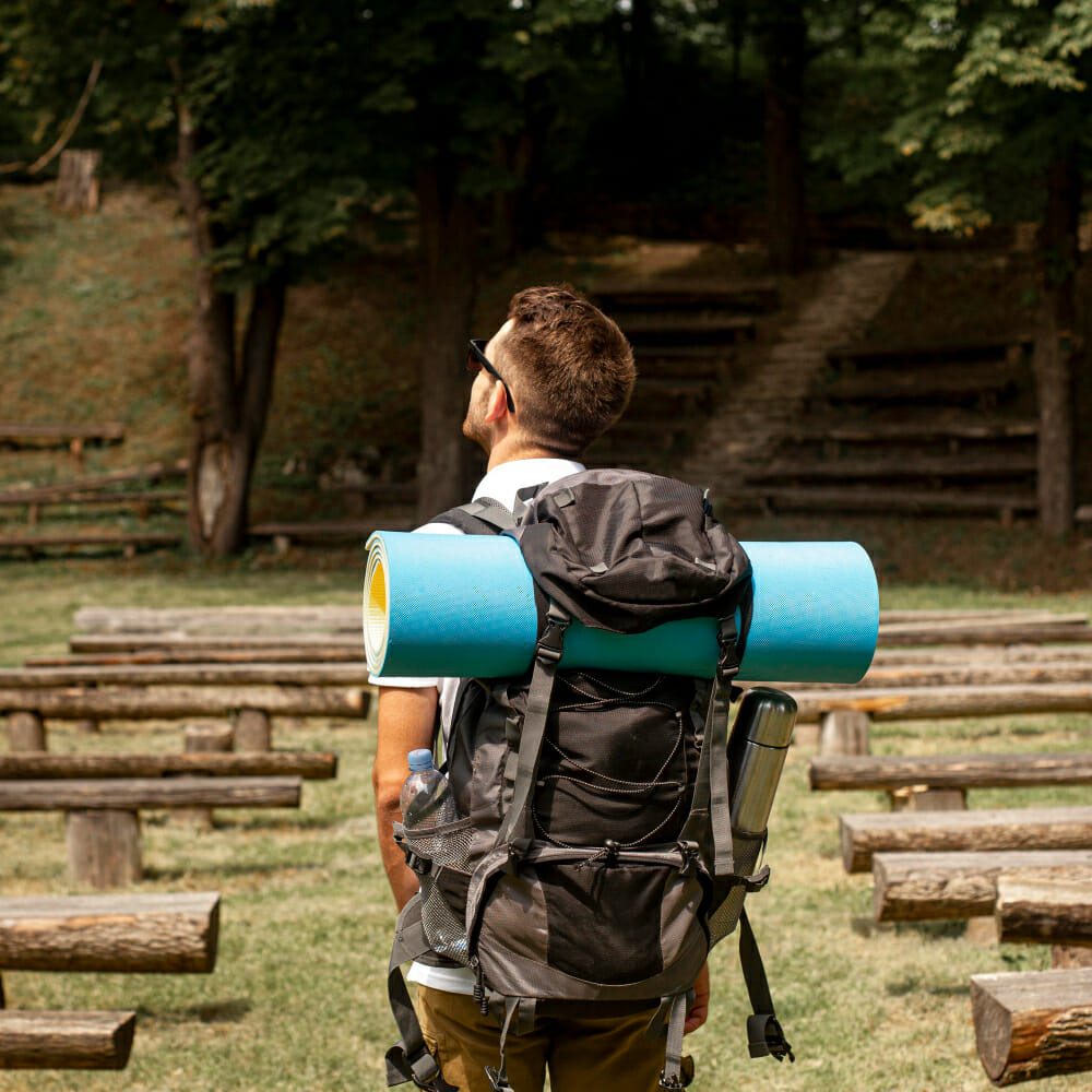 Sous le soleil éclatant, un homme de dos avance sur le chemin du pèlerinage vers Saint-Jacques de Compostelle. Son sac à dos bien rempli contient tout ce dont il a besoin, y compris un tapis de couchage pour les nuits sur le chemin. Ses lunettes de soleil protègent ses yeux tout en admirant la beauté époustouflante du paysage qui l'entoure. Une scène empreinte de sérénité et de dévotion, où chaque pas le rapproche davantage de son objectif spirituel.